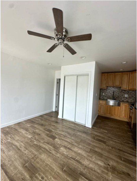 A room with a ceiling fan and wooden flooring.